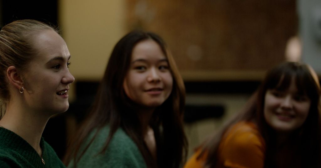 Tre blide ungdommer sitter sammen og snakker. Foto