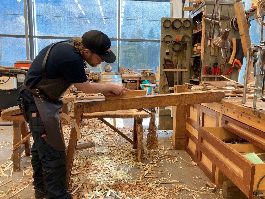 Mann jobber med trearbeid i verksted. Foto.
