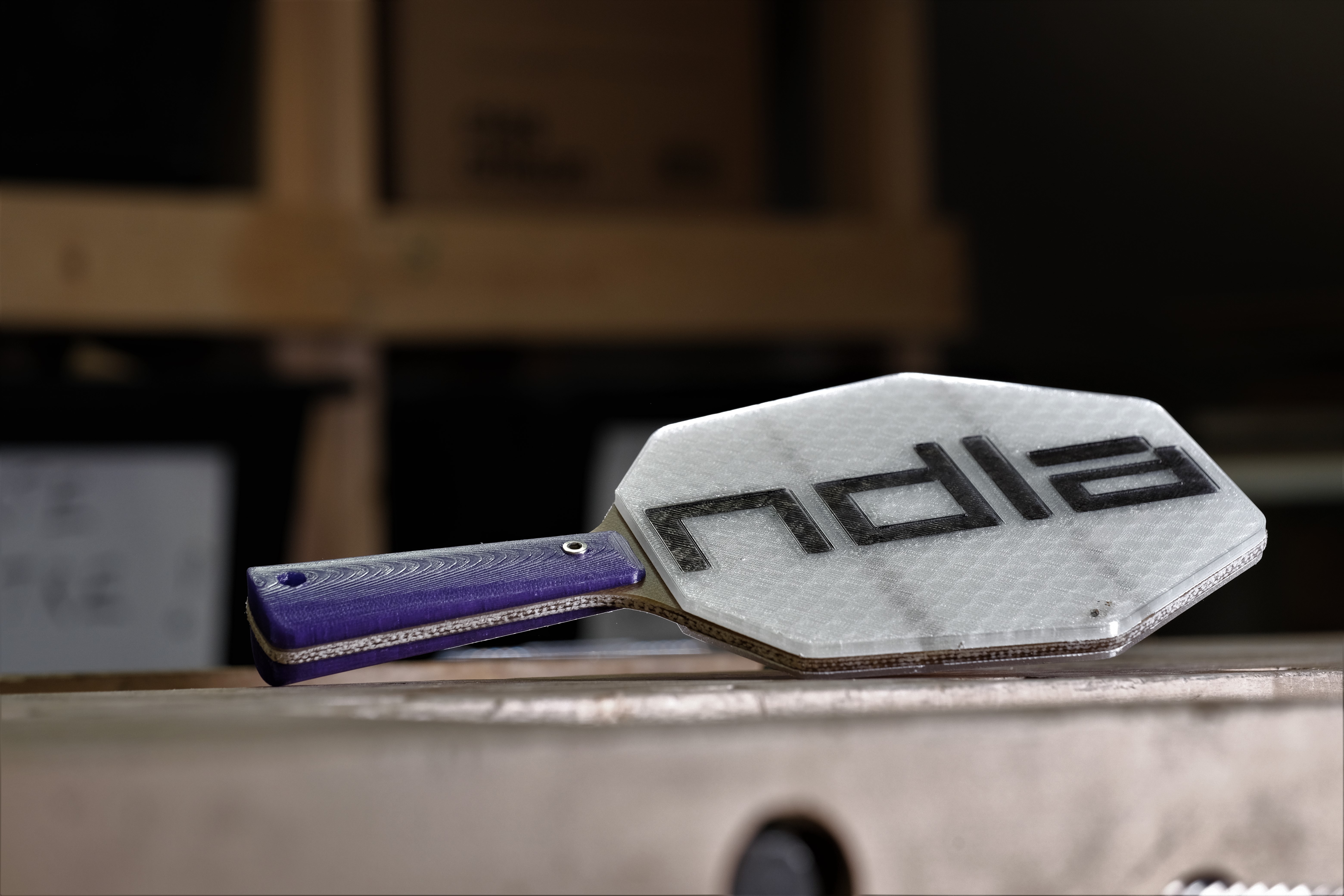 Ferdig rekkert med lilla håndtak og sekskanta slagflate med påskrifta NDLA. Foto.