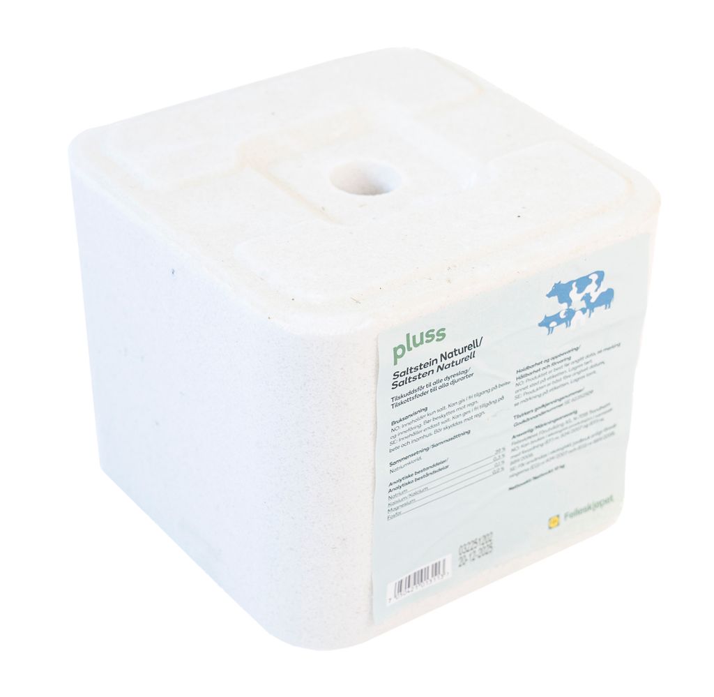 Hvit kubeformet saltslikkestein til husdyr. Den har et gjennomgående hull i midten så den kan festes på ei stang. Foto.