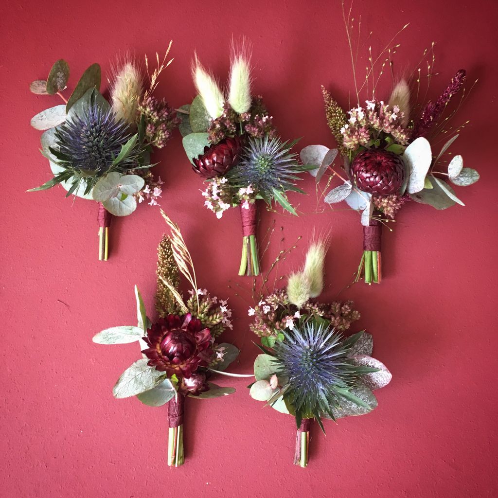 Fem ulike blomstersmykker som kan plasseres i knapphull. Foto.