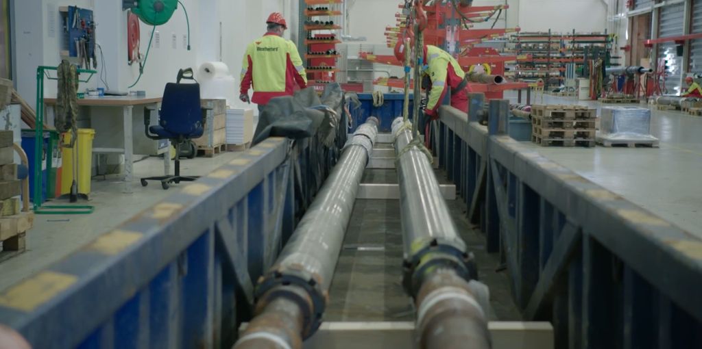 En åpen konteiner med lange rør pakkes klar for forsendelse offshore. Foto.