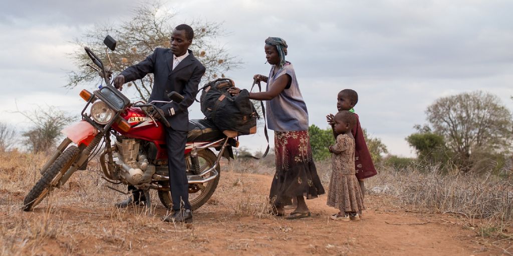 Kisilu on his bike surrounded, by his family. Photo.