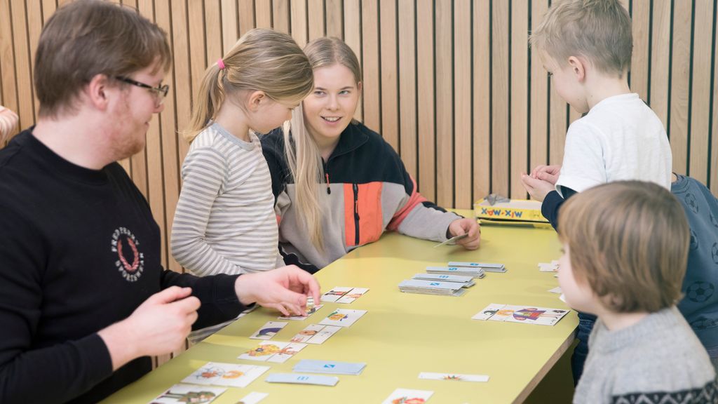 To vaksne SFO-leiarar speler spel med to gutar og ei jente. Foto.