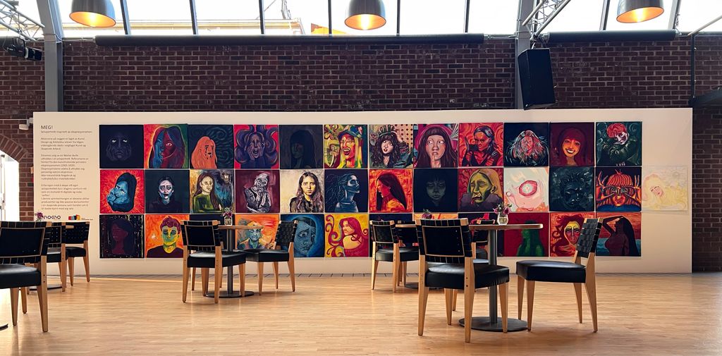 Gallerivegg med malerier i et kaféområde. Foto.