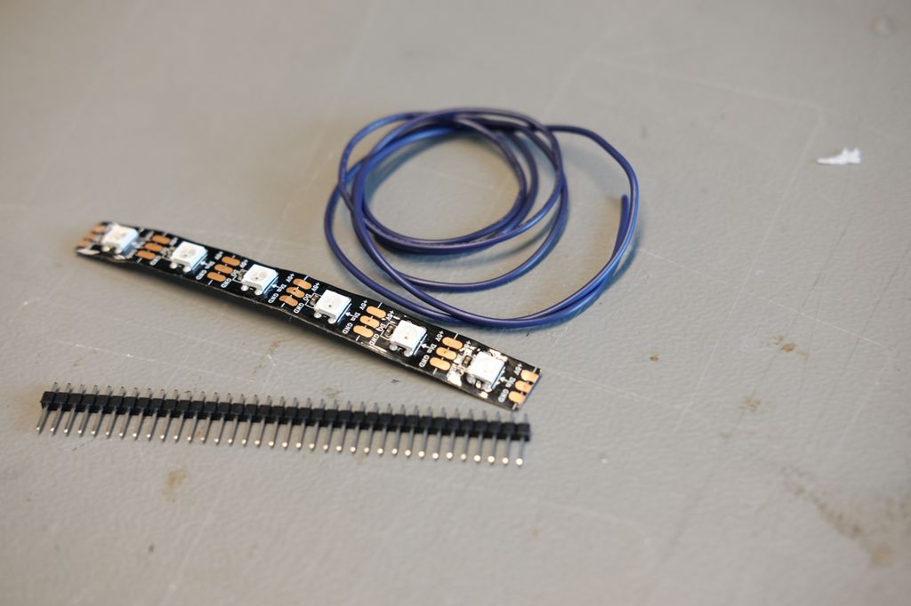 LED-stripe, ledninger og ei skinne med koblingspinner liggende på et bord. Foto.