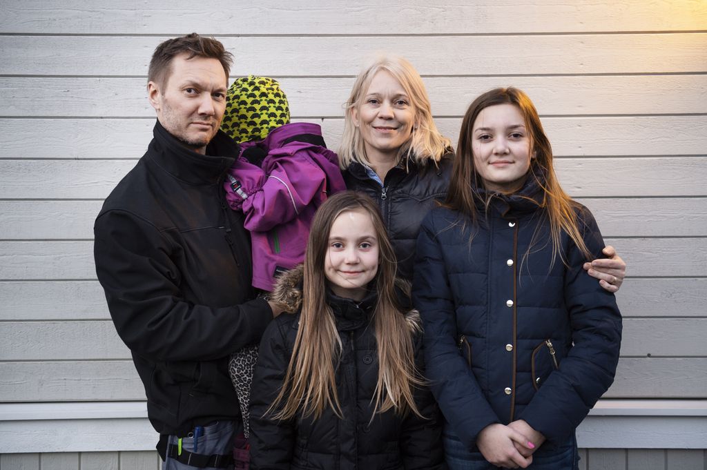 Mann, kvinne og tre barn i boblejakker foran en vegg med liggende bordkledning. Ett av barna er tenåring, ett er i barneskolealder og ett er i barnehagealder. Foto.