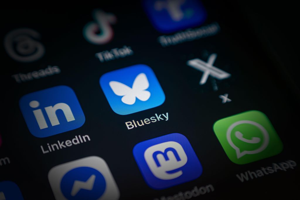 Digital skjerm med ulike app-ikoner, blant annet Bluesky, X, LinkedIn, WhatsApp og TikTok. Foto.