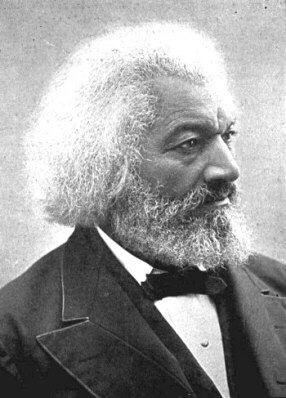 A photo of an old Fredrick Douglass. He is dressed in a suit and has white hair and a white beard. He looks away from the audience.  