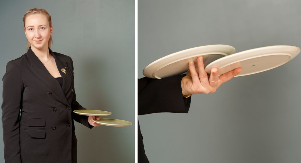 Ein servitør viser korleis ho held fingrane når ho ber to tallerkenar. Foto.