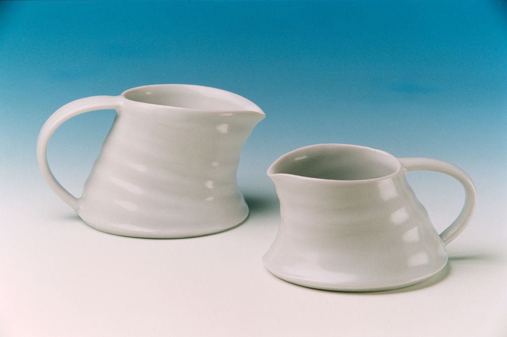 To hvite mugger som er dreide i leire. Formene er berabeidet etterpå. Foto.