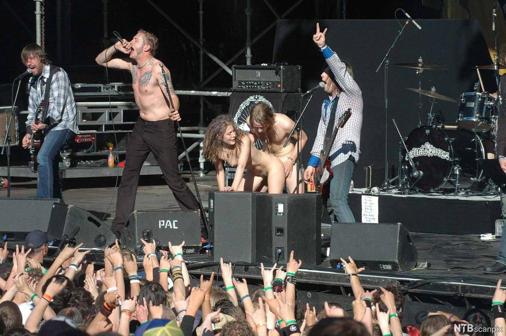 Eit rockeband speler mens ein mann og ei kvinne har sex på scena. Foto.