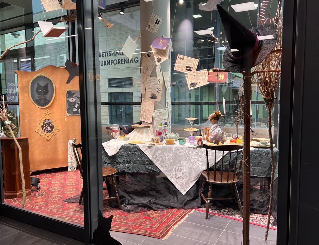 Et bord er overdådig dekket i et utstillingsrom. Omgivelsene er dekorert med halloween som tema. Foto.