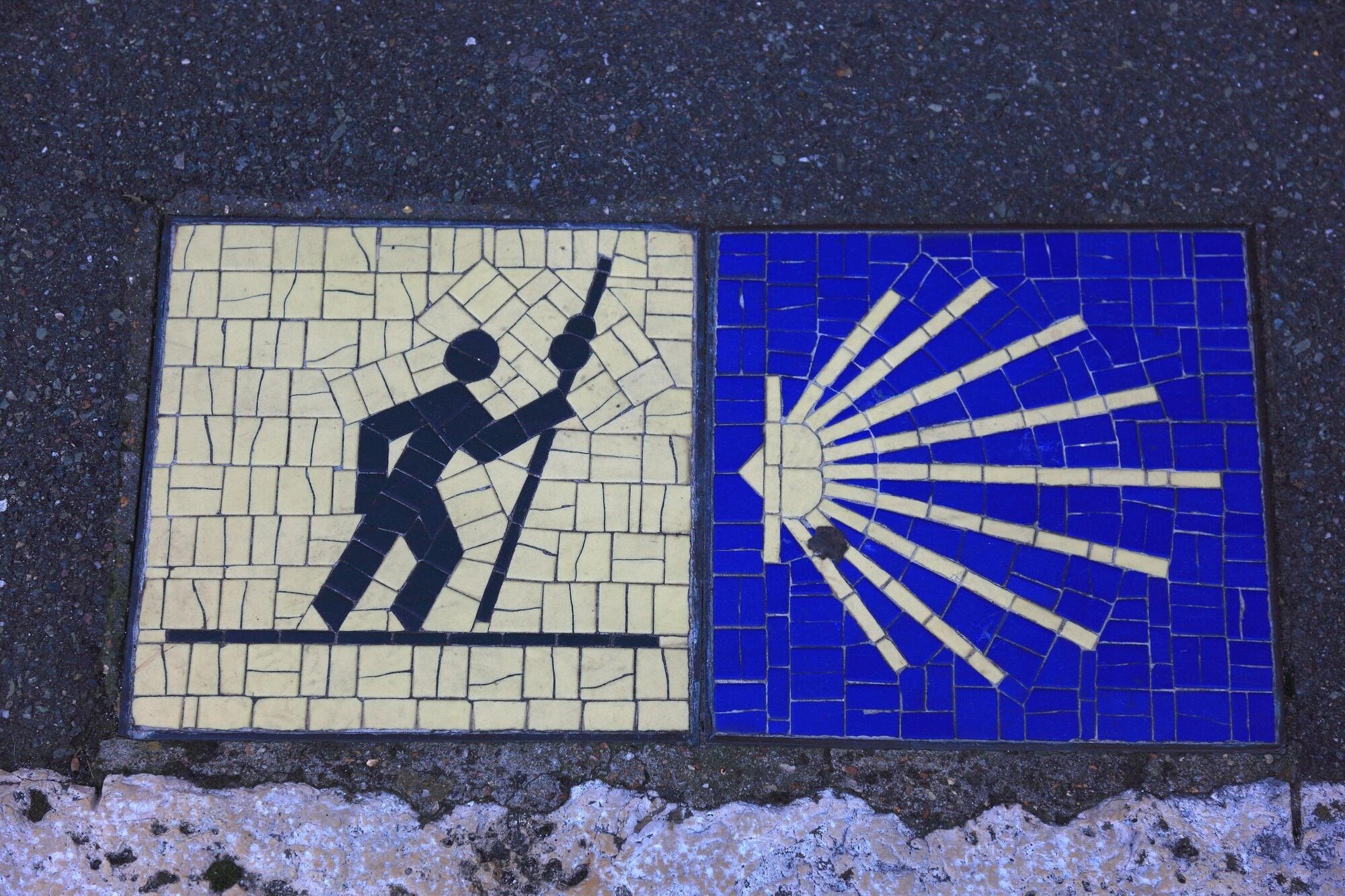 Mosaikk som består av to bilder. Det ene bildet har gul bakgrunn og viser en svart strekmann som går framoverlent med en lang stav. Det andre bildet har blå bakgrunn og viser noe som minner om ei strålende gul sol. Sola er hjerteformet og er til venstre i bildet, og strålene stråler ut mot høyre del av bildet. Foto.