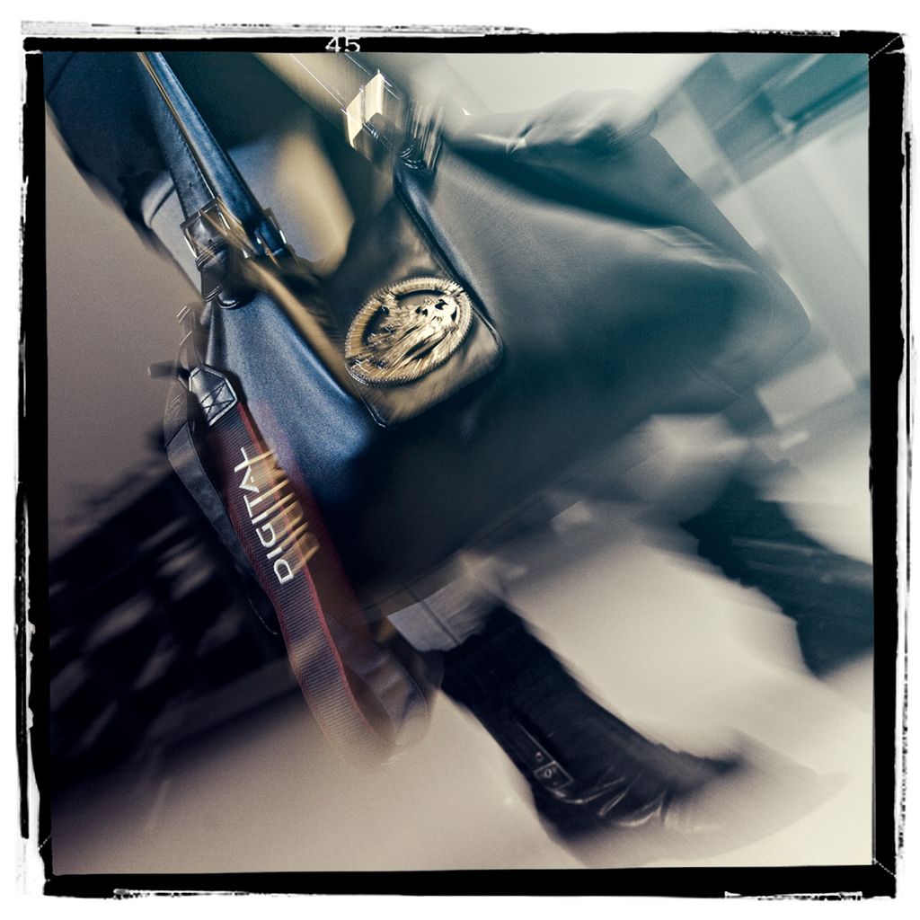 Dame med veske hvor kamerareimen henger utenfor. Foto.