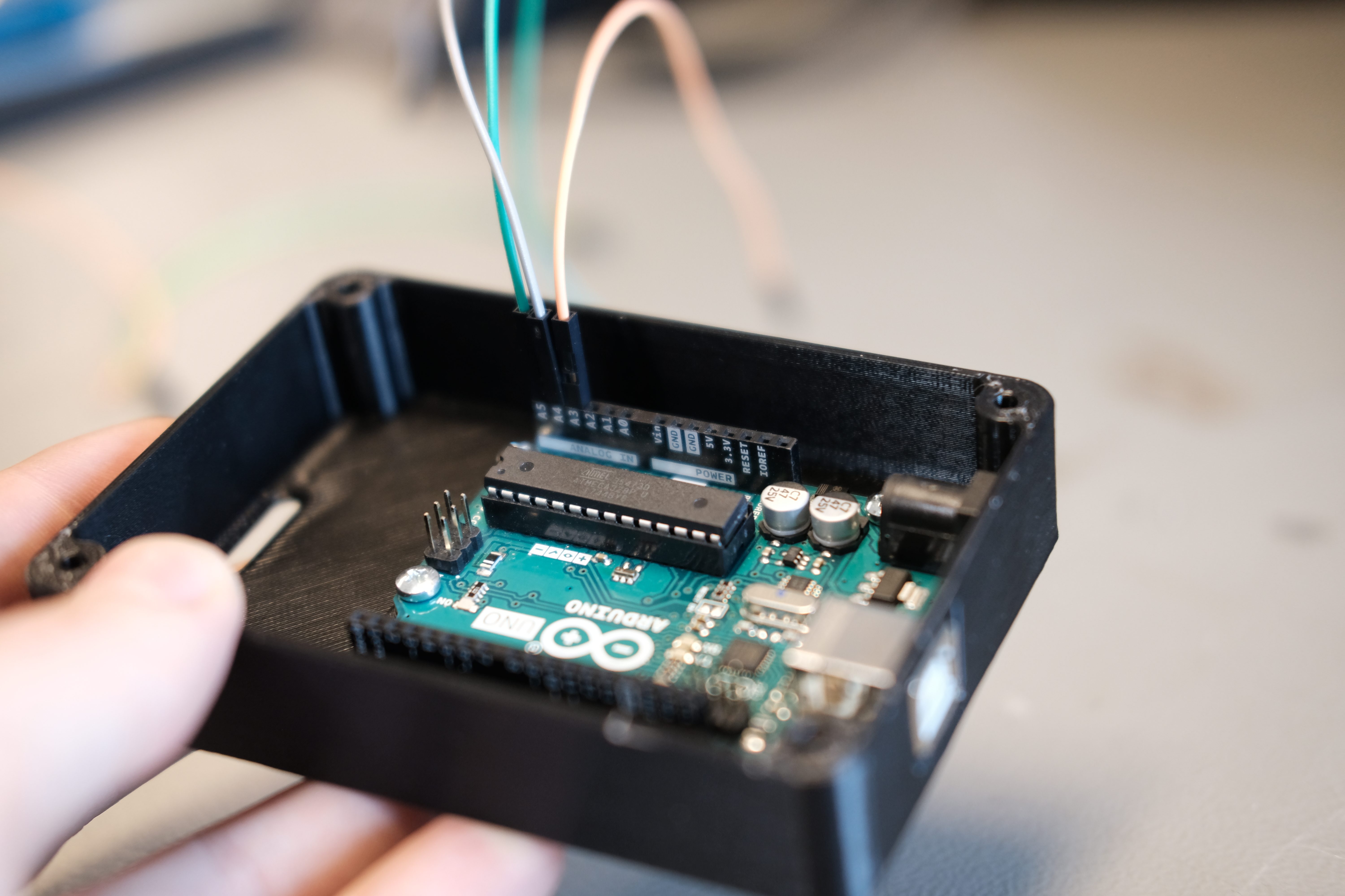 Rektangulær, 2–3 cm høy plastboks med en mikrokontroller av typen Arduino montert inni boksen. Foto.