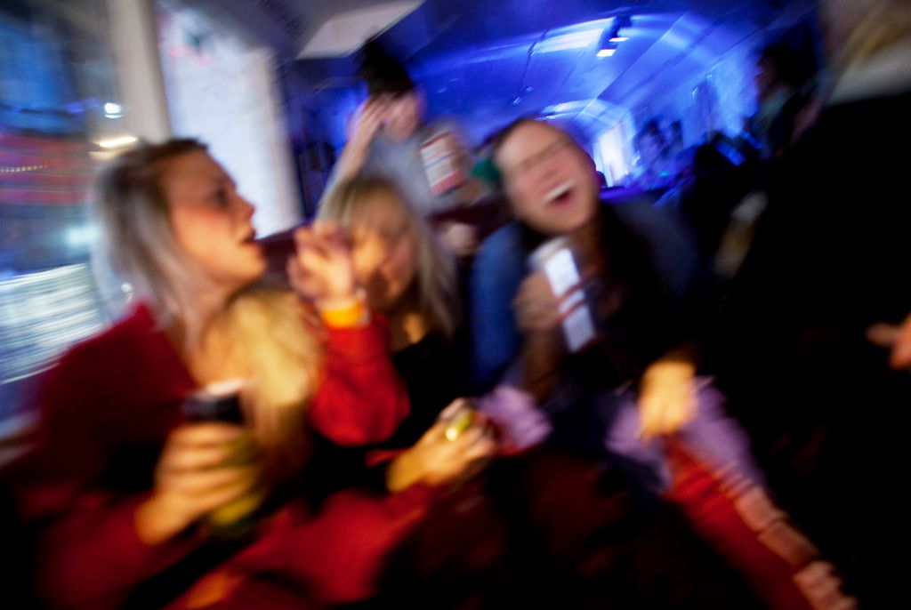 Uskarpt bilde av tre russ som fester inne i en buss. Foto.