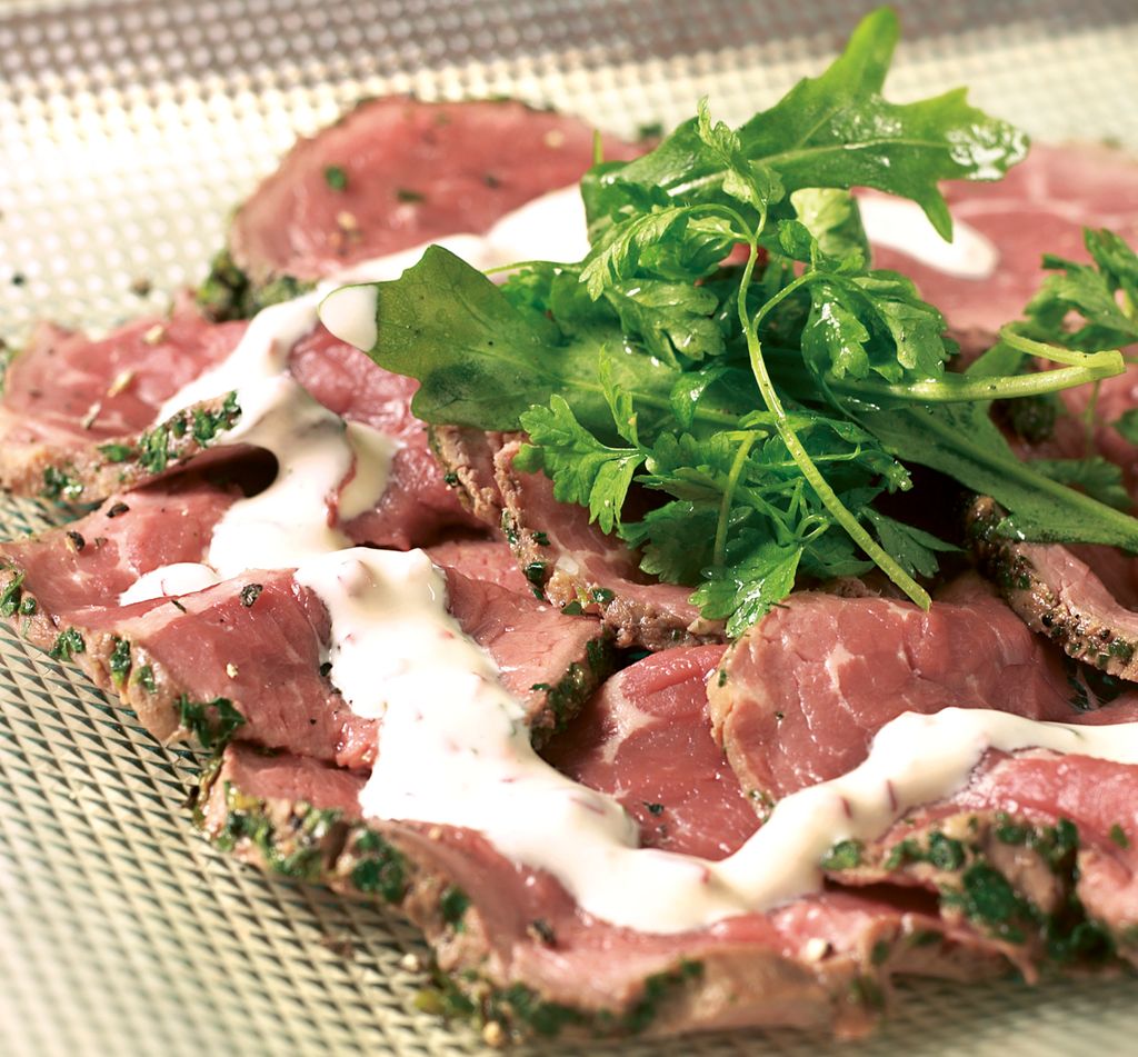 Carpaccio med garnityr på et blankt fat. Foto.