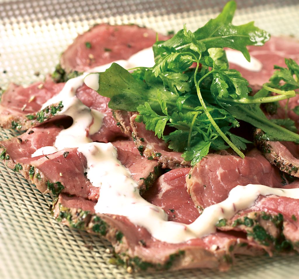 Carpaccio med garnityr på eit blankt fat. Foto.