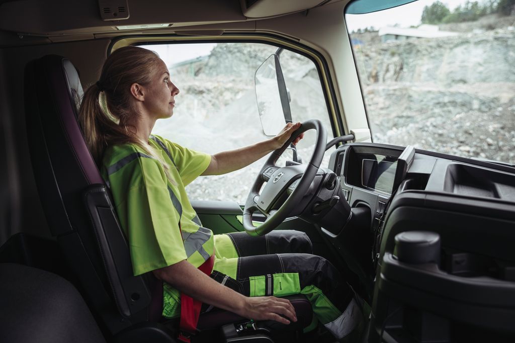 En kvinnelig yrkessjåfør bak rattet på en lastebil. Foto.