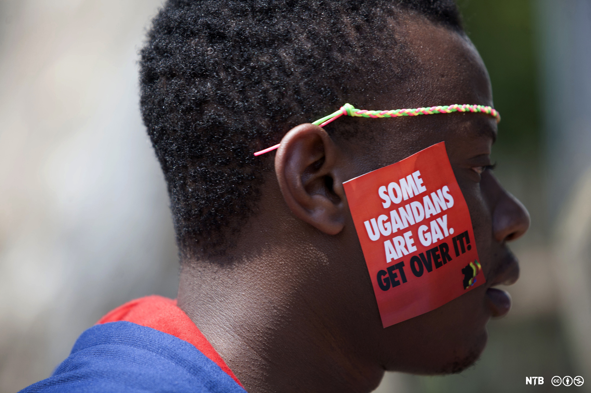 Photo: Black man with a sticker on his face that says 'some Ugandans are gay. Get over it!