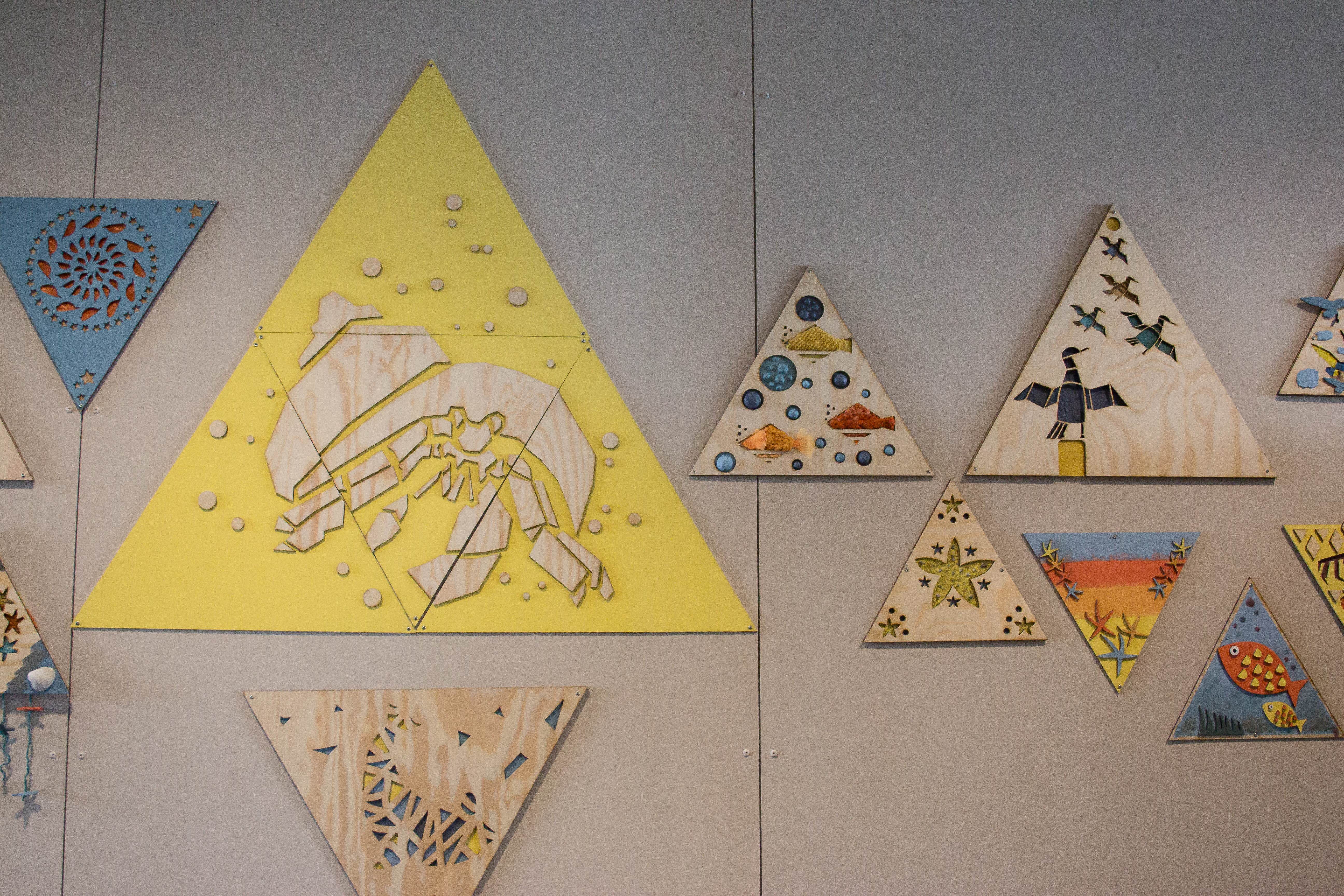 Bilder bestående av ulike materialer på en vegg. Foto. 