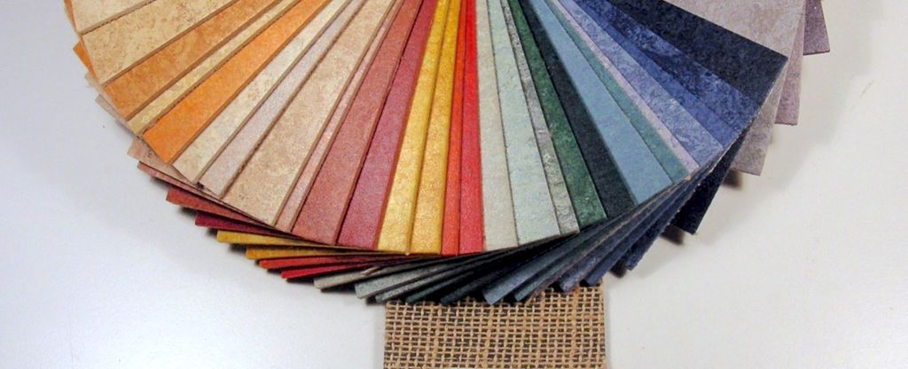Fargevifte som viser utvalget i linoleumsbelegg. Den ene materialprøven viser jute på baksida av gulvbelegget. Foto.