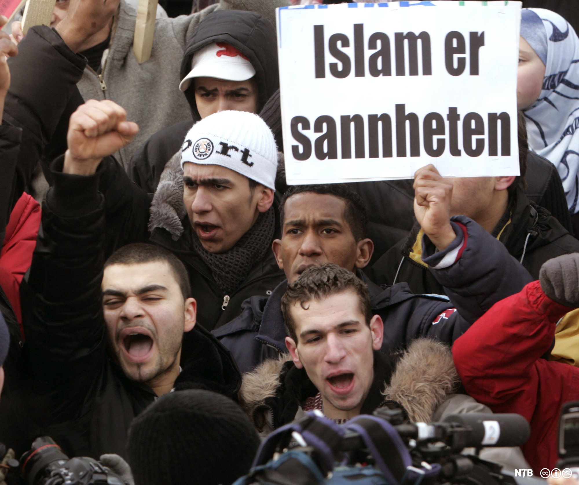 Ei gruppe unge menn held opp ein plakat med teksten: "Islam er sannheten". Foto.