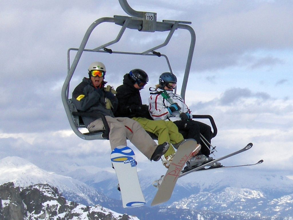 Tre slalom- og snowboardkjørere i en skiheis i Alpene. Foto.