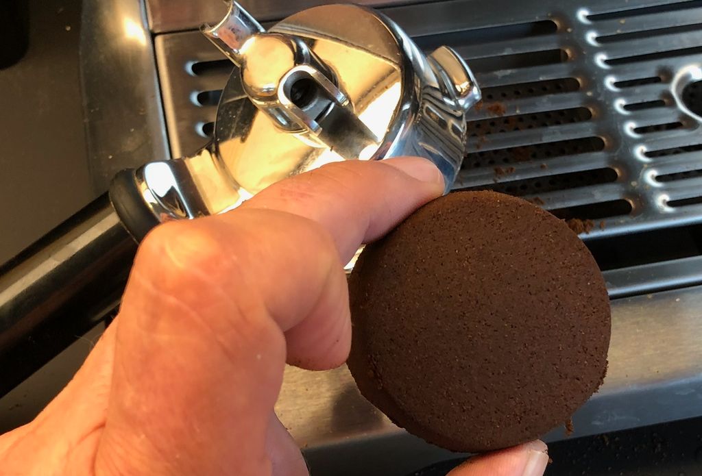 Ei hand held ei kaffikake frå ein espressomaskin. Foto.