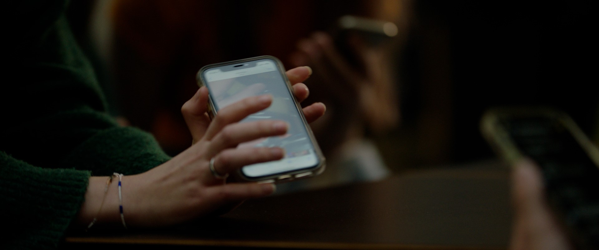 Ei hånd som holder en mobiltelefon og viser den fram. Foto.