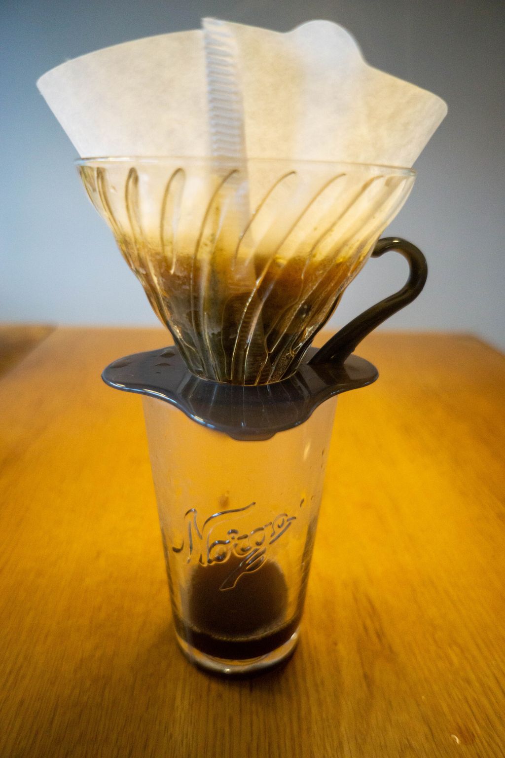 Kaffefilter i filterholder som står oppi  glass med påskriften "Norge". Foto.