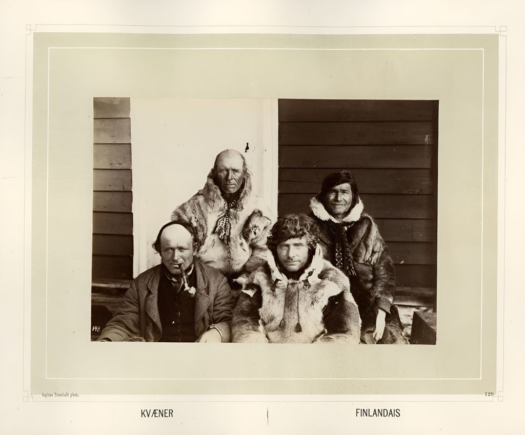 Fire menn sitter på ei trapp. Tre av dem er kledd i pesk og en i jakke. Det står Kvæner og Finlandais nederst på bildet. Svart-hvitt foto.
