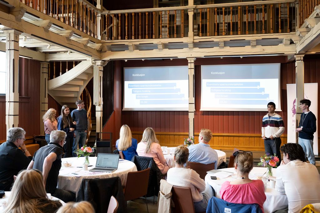 Fem elevar presenterer for ei forsamling vaksne. Foto.