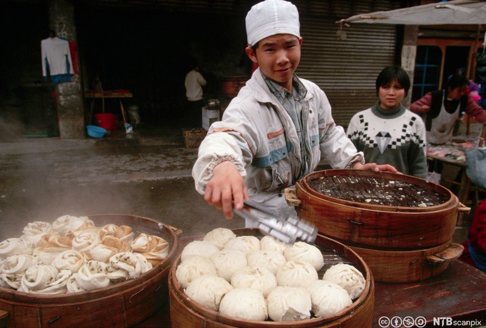 Ung mann damper og selger dumplings. Foto.