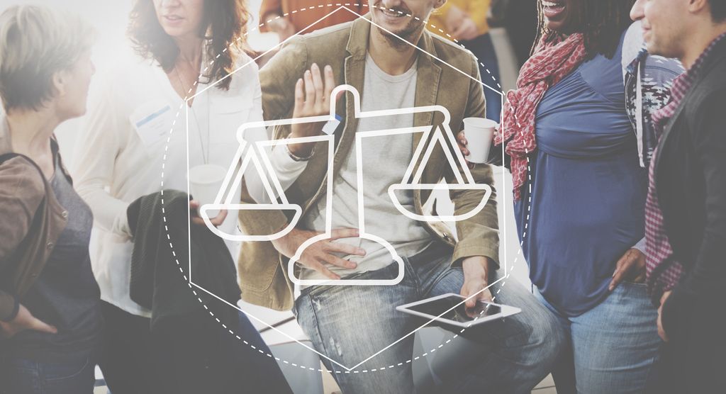 Fem ulike menneske står saman i ei gruppe og snakkar i lag. Ansikta deira er utanfor biletkanten. Ei teikna vektskål som illustrerer rett og galt, er i forgrunnen. Foto. 