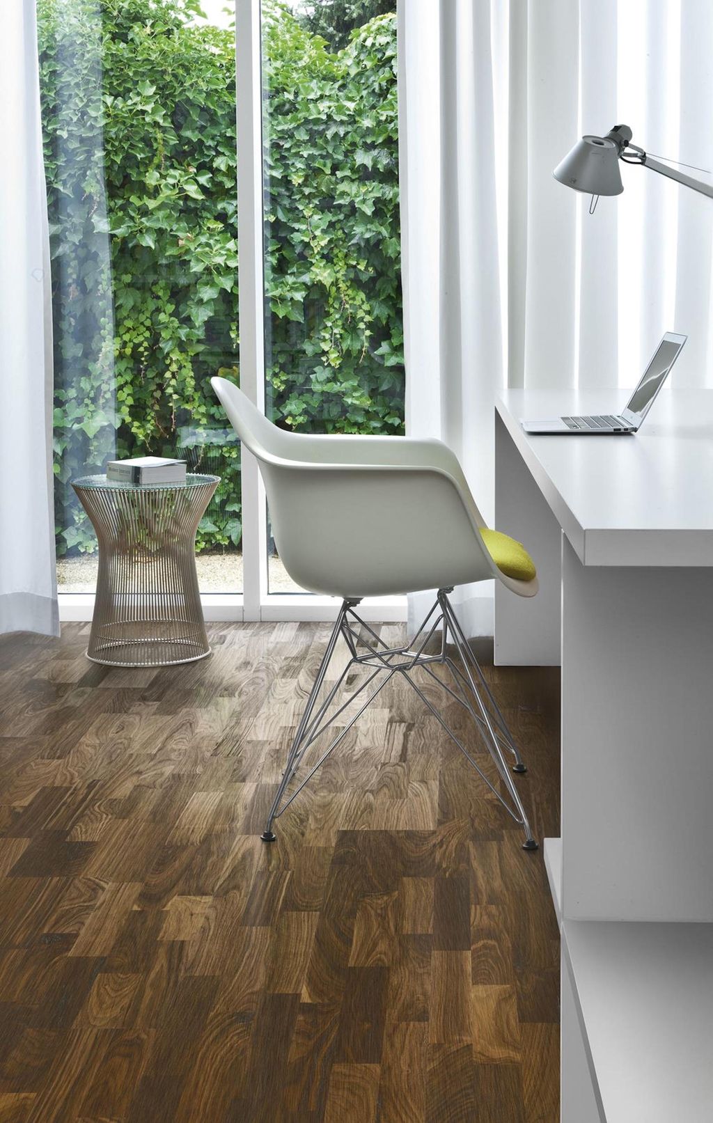 Hvit stol og arbeidspult på valnøtt-parkett. Foto.