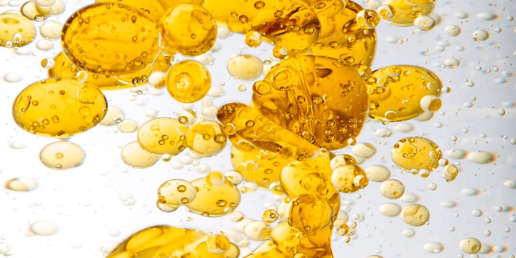 Oransje oljedråper i vann. Foto.