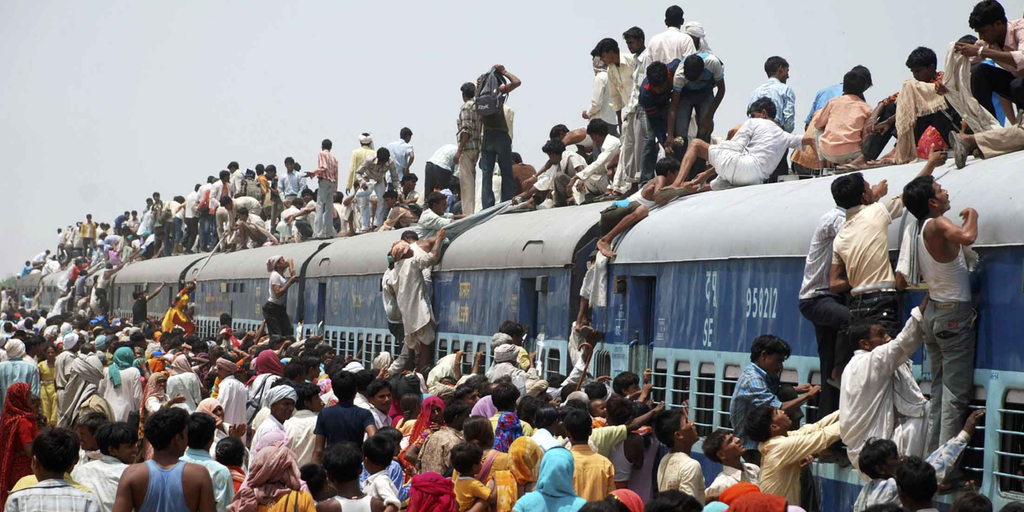Folkemengde i Asia klatrer opp på taket på et overfylt tog.  Foto.
