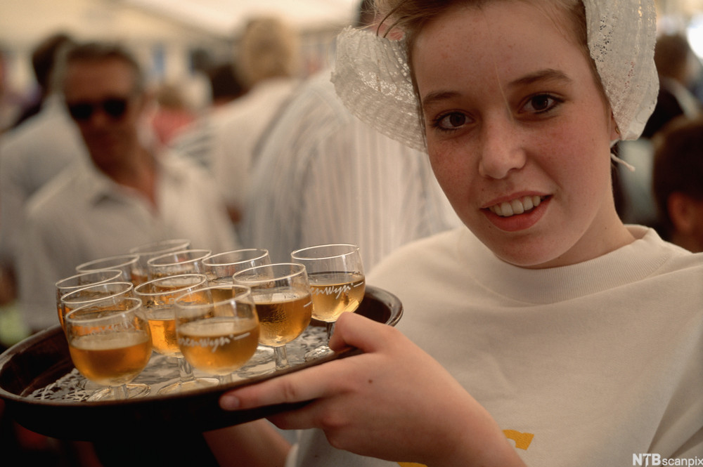 En servitør holder et brett med genever. Foto.