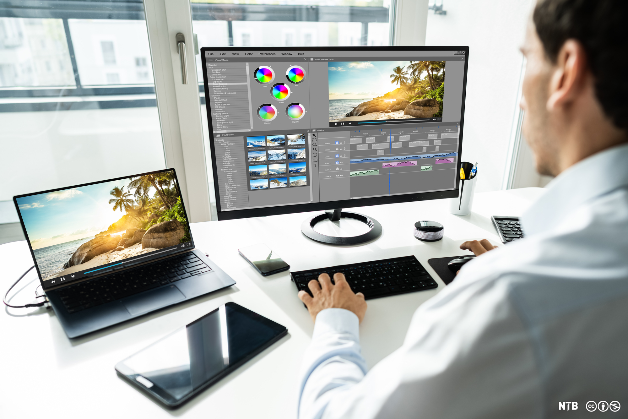 Mann sitter foran en stasjonær datamaskin og redigerer et bilde av en strand. Foto. 