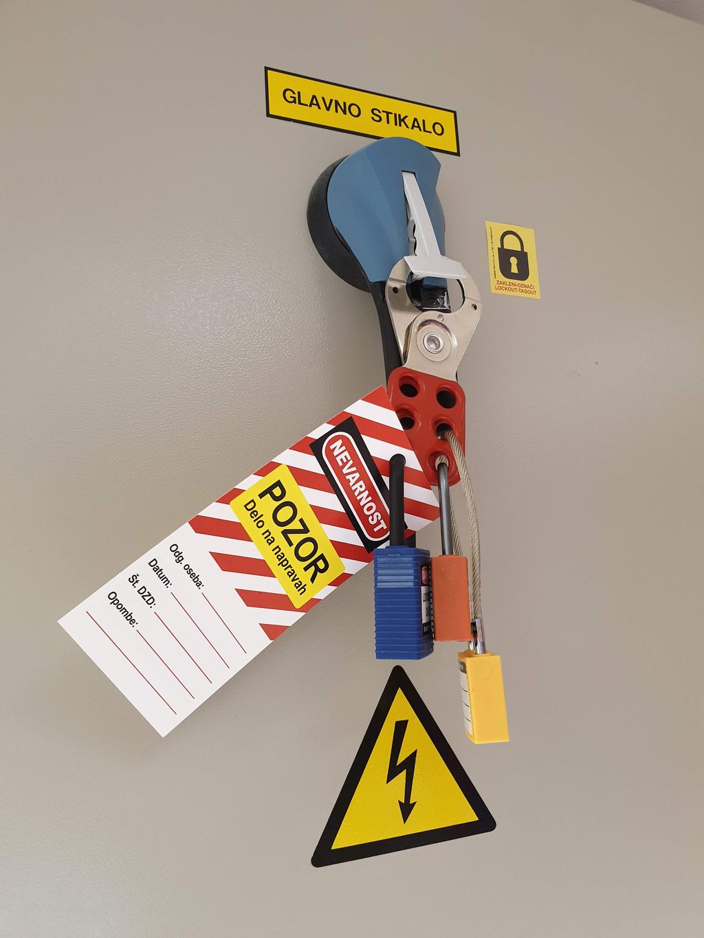 Strømbryter som er låst med tre hengelåser og utstyrt med en varsellapp. Foto.