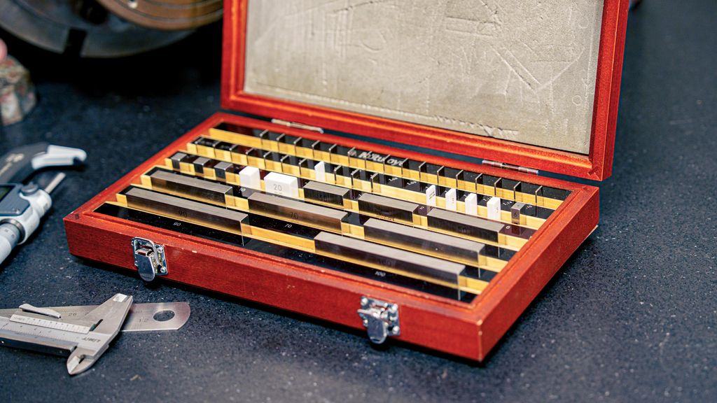 Brun eske med åpent lokk. I esken står det små metall- og porselensbiter. Foto.