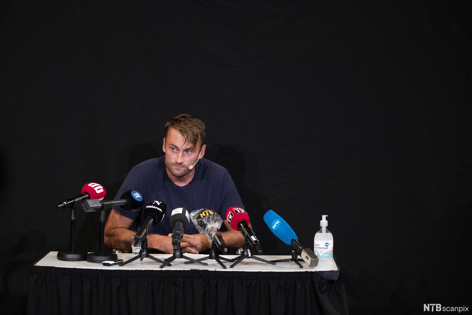 Petter Northug sitter bak en rad mikrofoner på en pressekonferanse. Foto.
