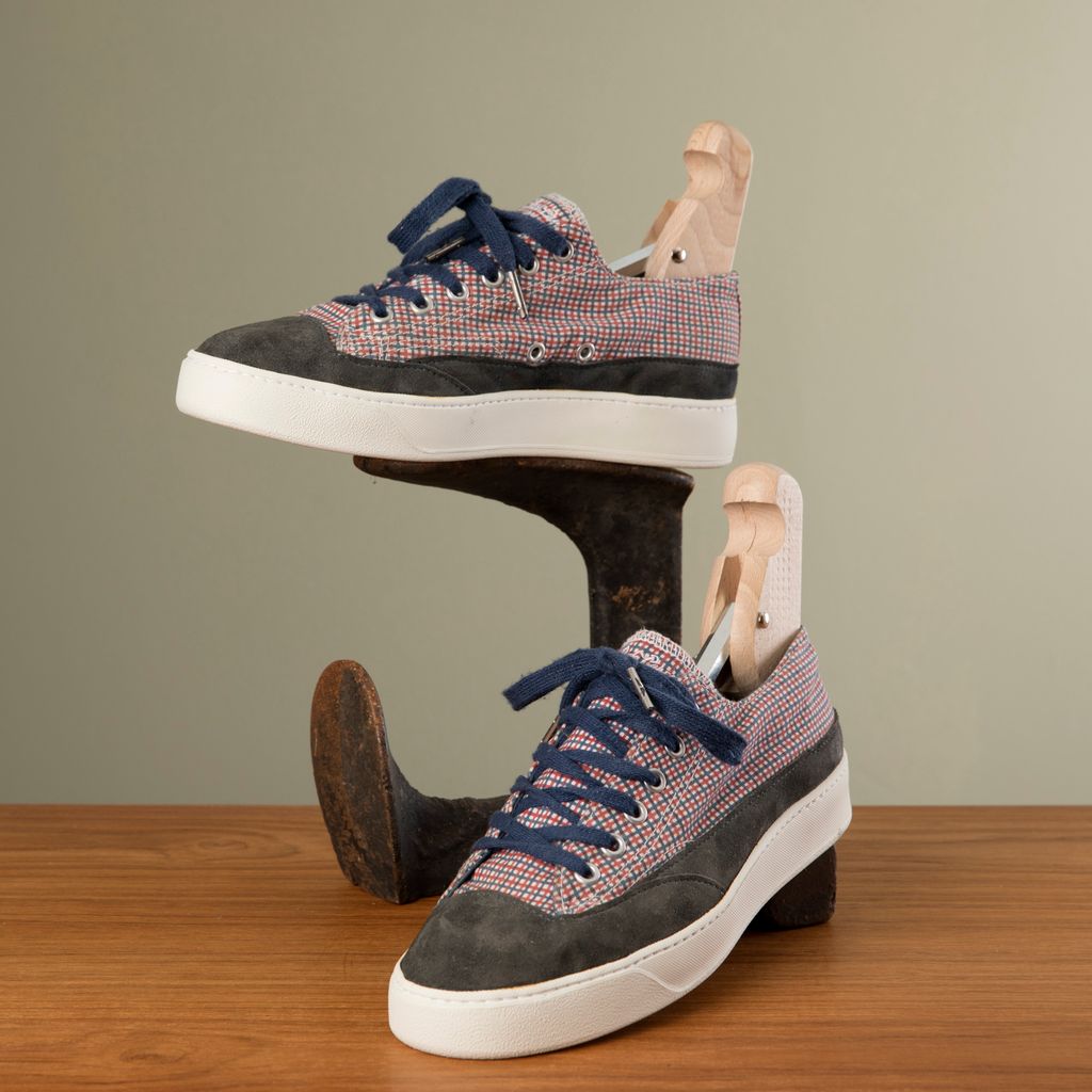 Sneakers i rutete stoff og semsket skinn er utstilt sammen med skomakerlester. Foto.