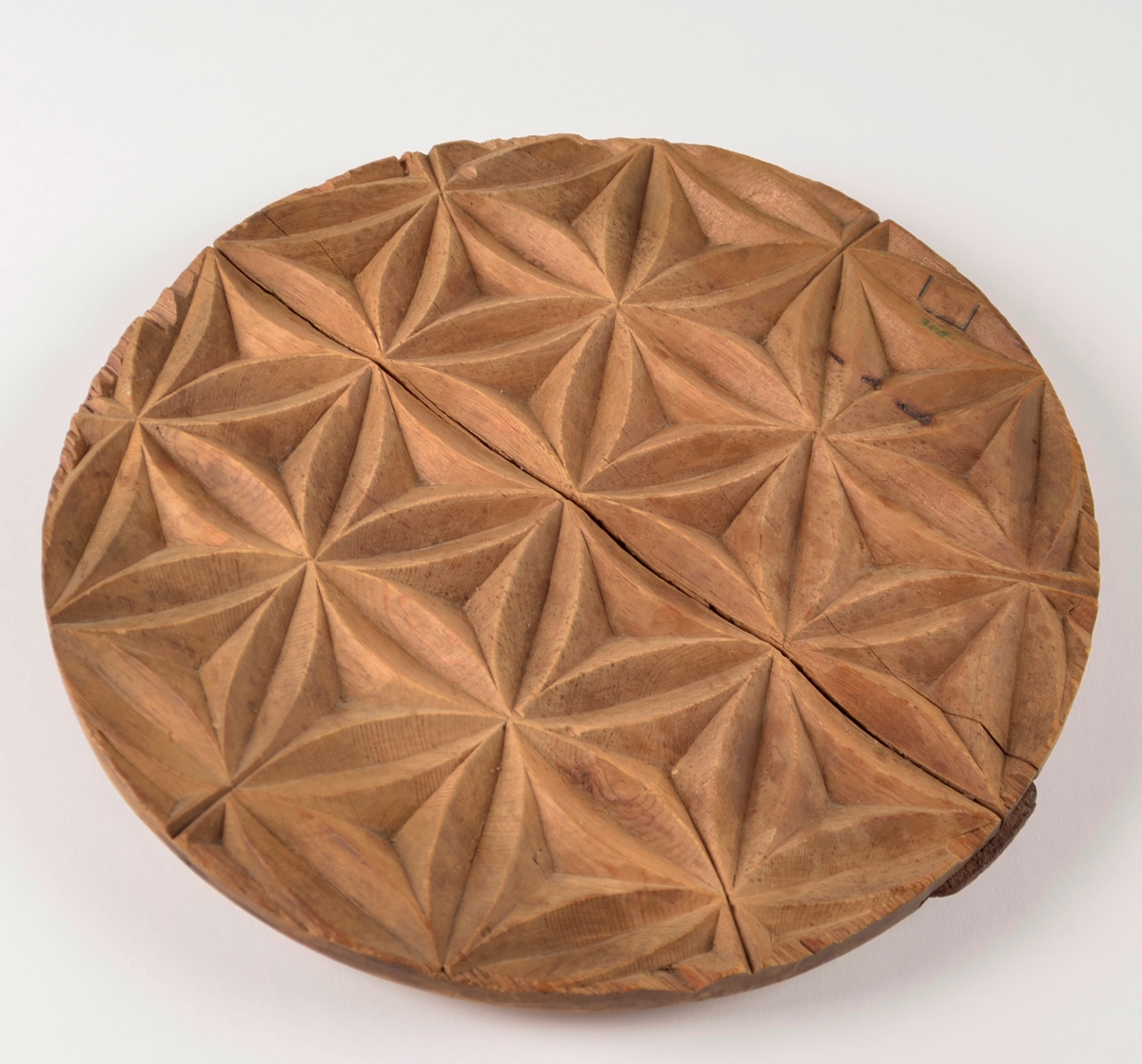 Sirkelformet treplate med geometrisk mønster utskåret. Foto. 