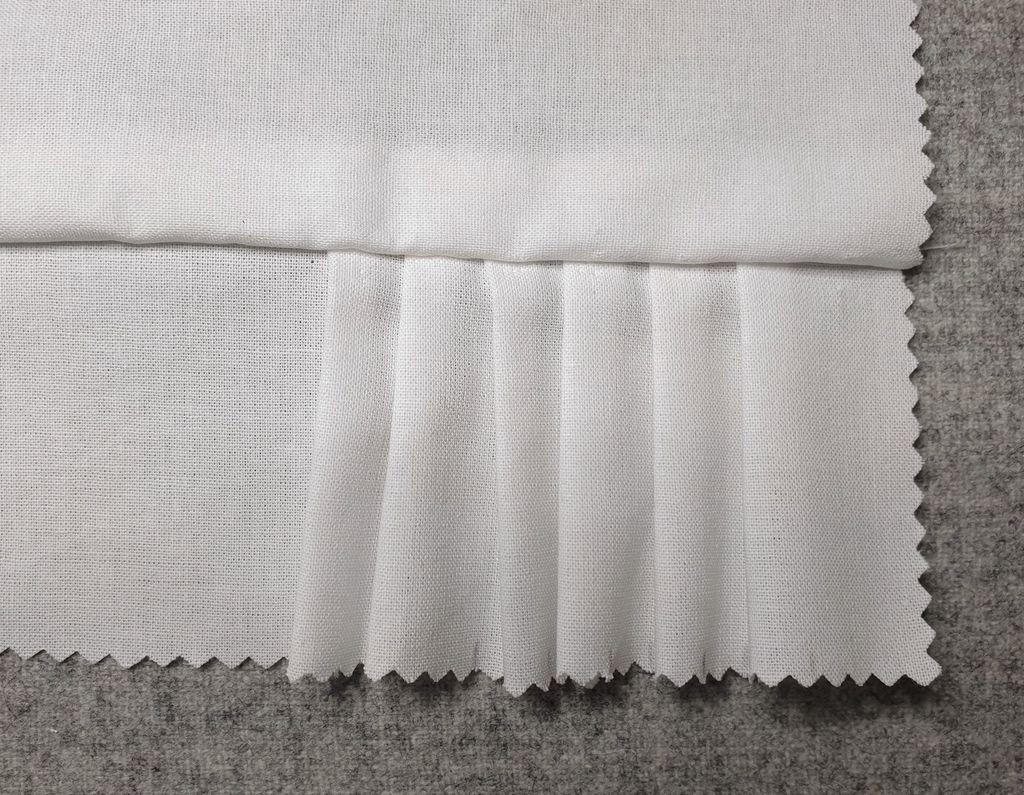 Fotografi av prøvelapp med maskinsydde faldar.