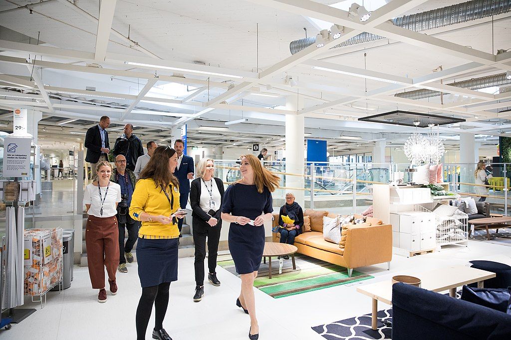En IKEA-medarbeider i uniform hjelper en kunde i møbelavdelingen. Foto.