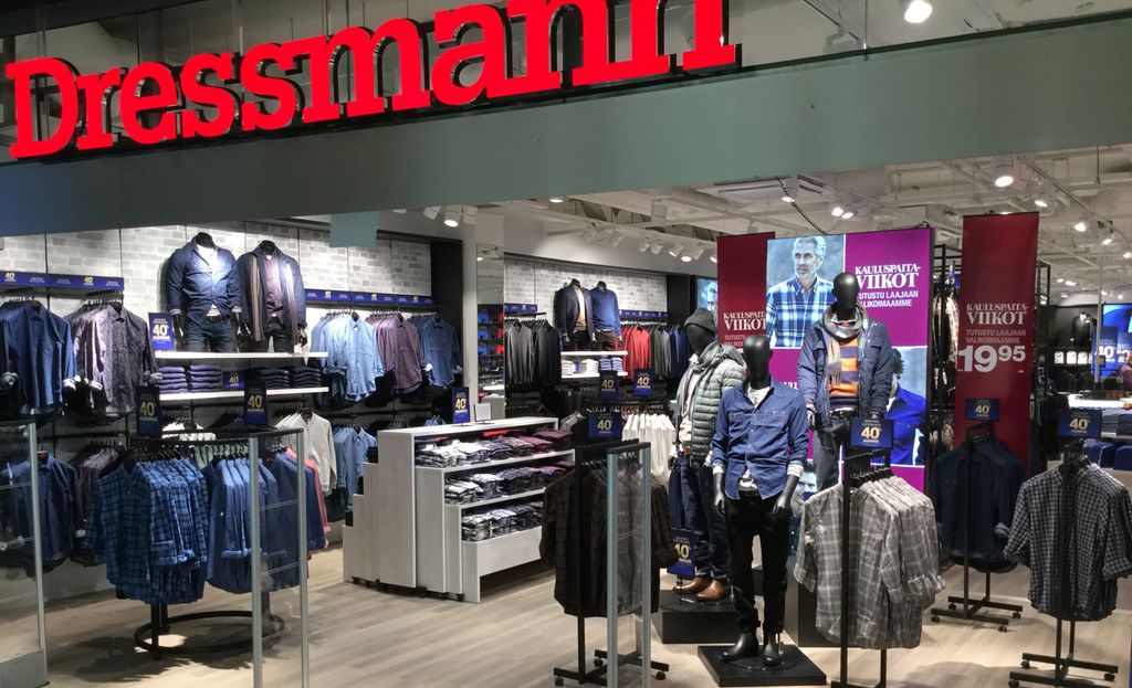 Skjorter og andre klær henger utstilt i en Dressmann-butikk. Det er også plakater rundt omkring i lokalet, og stativene har prisplakater. Foto.