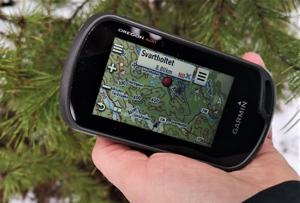 Hånd som holder en GPS-mottaker med kart på skjermen. Foto.
